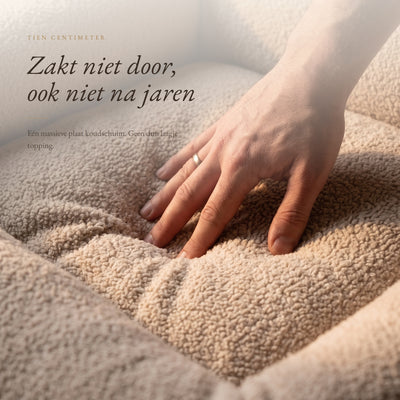 Hand drukt in het koudschuim van de beige hondenmand, het zakt niet door
